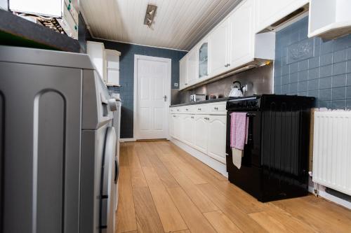 uma cozinha com armários brancos e um frigorífico preto em Malvern - Beautiful 2 bed upper flat Ideal for Contractors Free Parking em South Shields