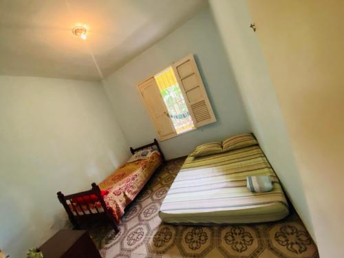 a small bedroom with a bed and a window at Sítio arco íris in Mauá