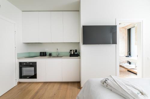 a white kitchen with white cabinets and a bed at GM exclusive Luxury Suites & SPA in Sitia