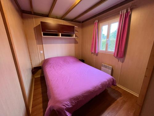 un pequeño dormitorio con una cama morada. en Les maisonnettes du lac - base de loisirs Lavaré en Lavaré
