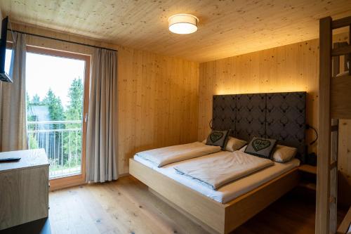 Un dormitorio con una cama en una habitación con ventana. en Holzhaus "Zum Schwarz'n", en Aurach am Hongar