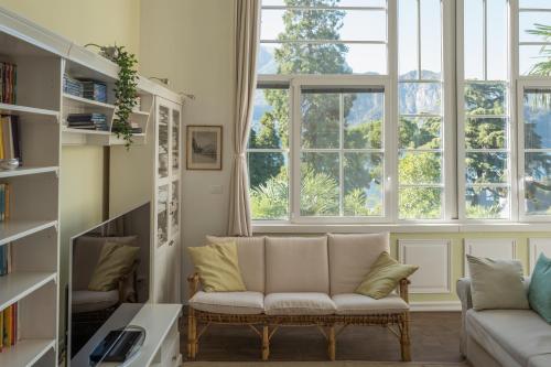 a living room with a couch and two windows at Bellagio Vintage Apartment in Bellagio