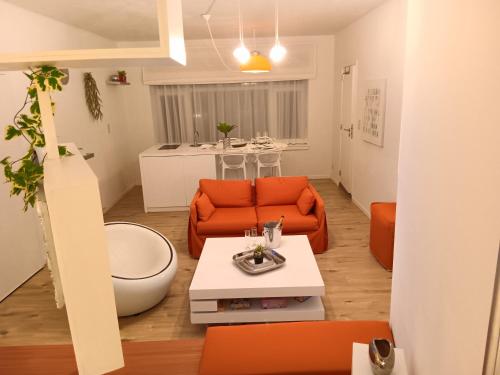 The Luxury White Suite في شارلوروا: غرفة معيشة مع أريكة برتقالية وطاولة