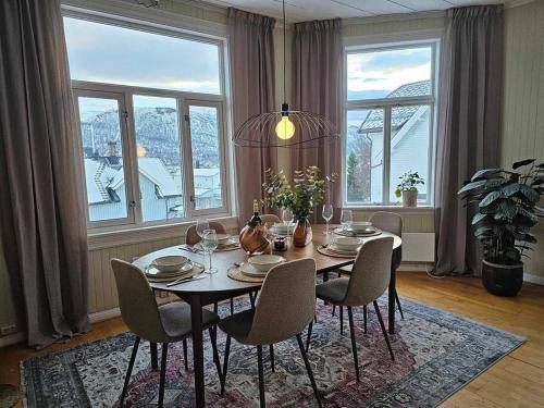 een eetkamer met een tafel, stoelen en ramen bij Amazing Tromsø city apartment with free parking and lovely city views! in Tromsø