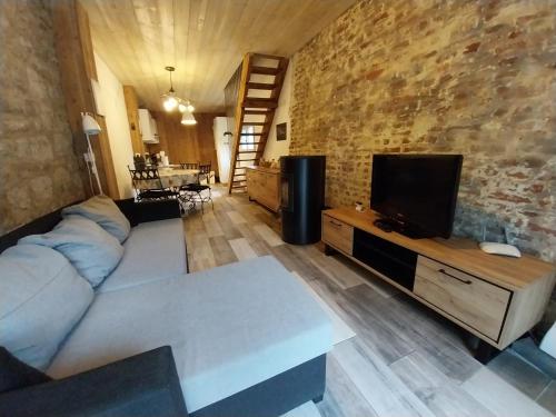 uma sala de estar com um sofá e uma televisão em Gîte La Grange em Chooz
