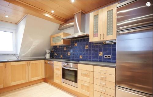 a kitchen with wooden cabinets and a stainless steel refrigerator at Ferienwohnung Tannen-Apotheke Zwei ab 5P mit drittem Schlafzimmer und extra Dusche WC in Mengerskirchen