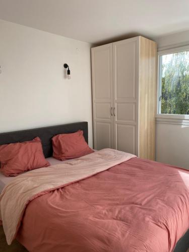 a bedroom with a large bed with red sheets and a window at Cosy home à 20min de paris et orly, Parking gratuit in Antony