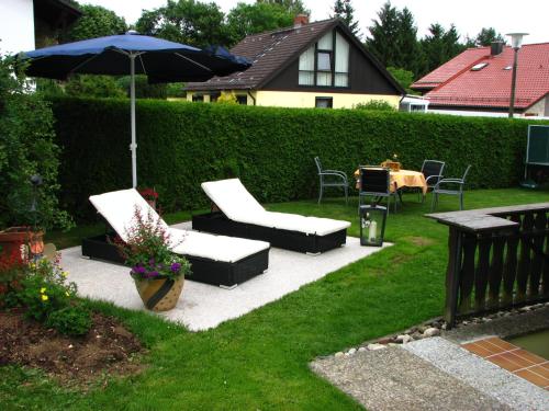 een patio met 2 stoelen, een parasol en een tafel bij Gegg`s Fe-Wo oder Doppelzimmer in Dollnstein