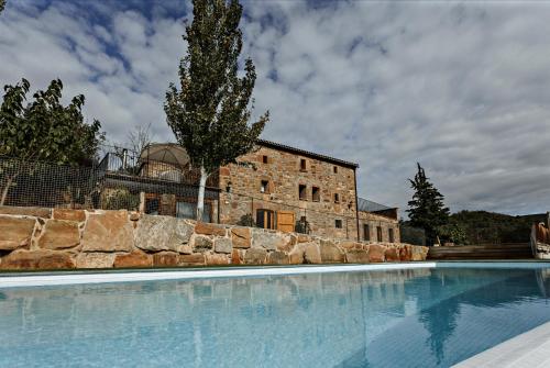 a large swimming pool in front of a brick building at Masoveria la Boba in Vilanova de la Aguda