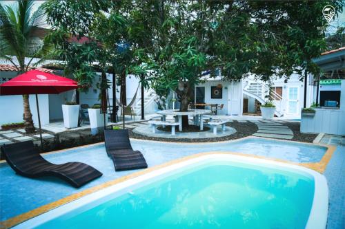 a swimming pool with chairs and a table and an umbrella at Blue Sand House B&B in Cartagena de Indias