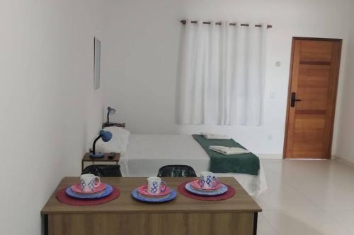 una habitación con una mesa con dos tazas y platos. en Loft LISBOA para Casais, em Iguaba Grande, 3 Pessoas, 150 metros da praia en Iguaba Grande