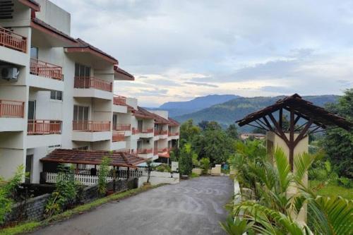a street in a resort with mountains in the background at ‘The Mountain Majesty’: cozy 1 bhk apartment in Karjat