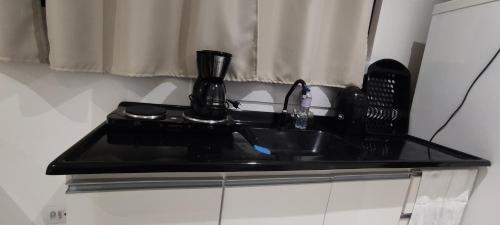 a black counter top with a sink in a kitchen at La Home House1 - Apto Studio Confortável em SJP - 10 minutos Aeroporto - Curitiba in São José dos Pinhais