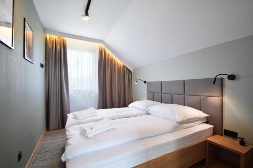um quarto com uma grande cama branca com almofadas brancas em Boska Gąska Domki Wypoczynkowe em Gąski