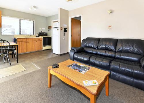 a living room with a leather couch and a table at Classique Lodge Motel in Christchurch