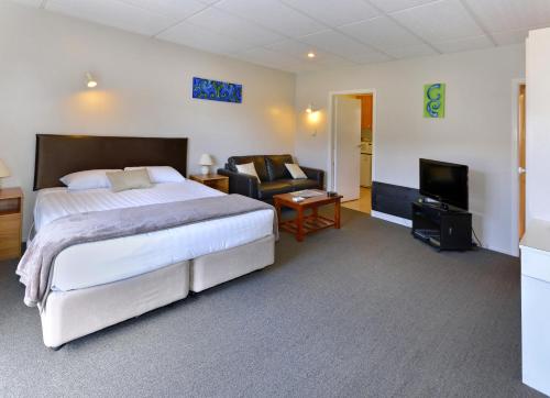 a bedroom with a bed and a couch and a television at Classique Lodge Motel in Christchurch