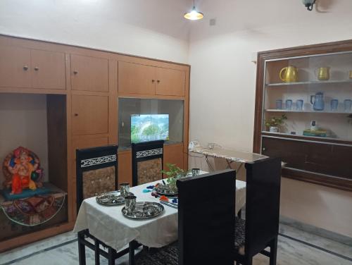 Vanita home stay في أودايبور: غرفة طعام مع طاولة وكراسي وتلفزيون