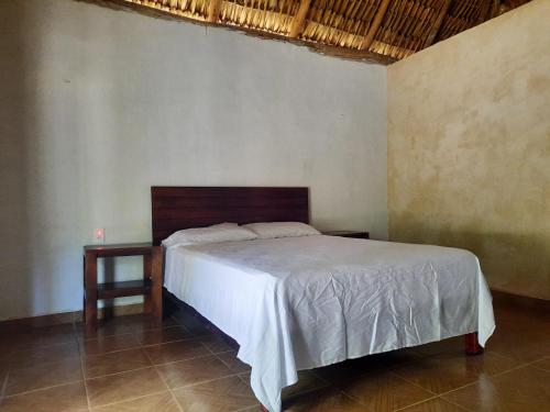 a bedroom with a large bed with a wooden headboard at Hotel Cabañas Maalokin in Cobá