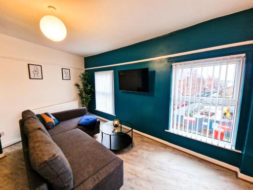 een woonkamer met een bank en een flatscreen-tv bij Modern and spacious apartment! in Liverpool