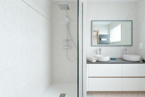 a white bathroom with a shower and a mirror at Villa Vue Mer in Lanildut
