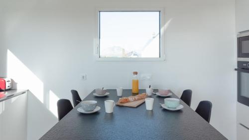 a kitchen with a black table and chairs and a window at Villa Vue Mer in Lanildut