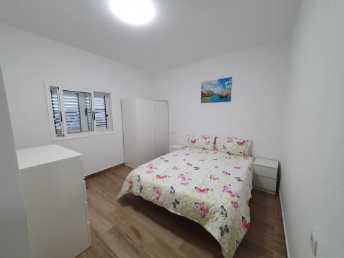 Dormitorio blanco con cama con colcha de flores en Casita isabelita, en Valle de Santa Inés