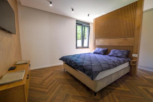 a bedroom with a bed with a wooden headboard at Villa Diamond One in Banja Luka