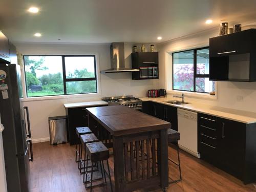 a kitchen with black cabinets and a wooden table at Kereru Cottage in Kaikoura