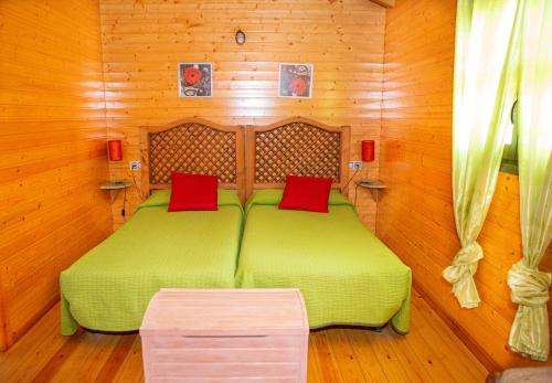 a bedroom with a green bed with red pillows at Apartamentos Rurales El Rincón del Jerte in Rebollar