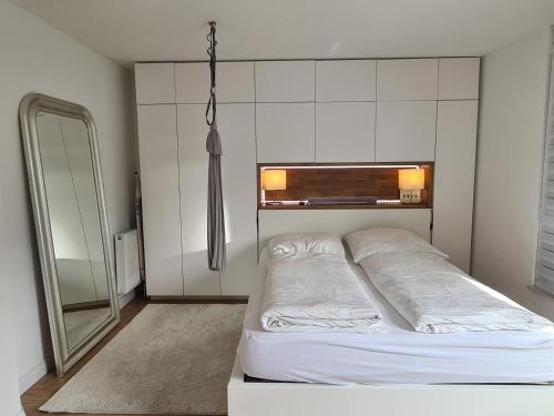 a white bedroom with a bed and a mirror at Privatzimmer an der Messe in Hannover