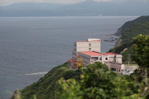 a building on top of a hill next to the ocean at Hotel Tappi in Satogahama