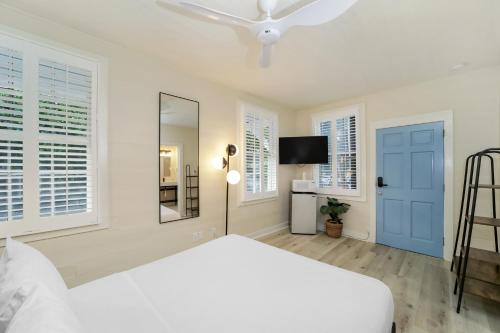 a white bedroom with a white bed and a blue door at Tranquillity Guest House in Key West