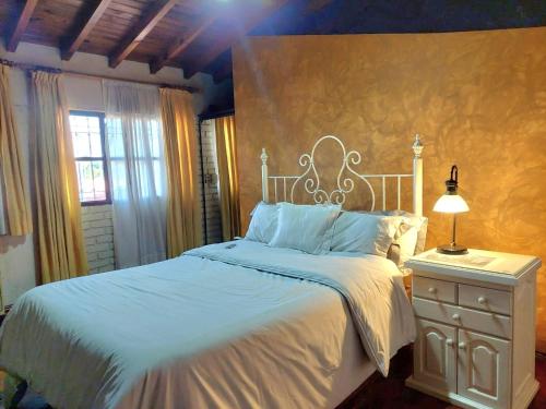 um quarto com uma cama branca e uma mesa com um candeeiro em Habitación con baño privado y estacionamiento em San Martín