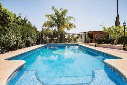 a swimming pool with blue water in a yard at Guest house with shared pool. in Coria del Río