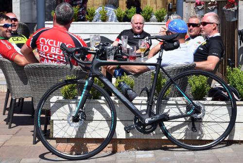 um grupo de pessoas sentadas numa mesa com uma bicicleta em The Greyhound Inn and Hotel em Usk