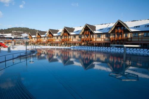 ein Resort mit schneebedeckten Gebäuden und einem Pool mit Wasser in der Unterkunft Bešeňová Apartmán Relax in Bešeňová