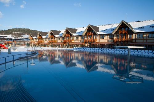 a resort with snow covered buildings and a pool of water at Bešeňová Apartmán Relax in Bešeňová