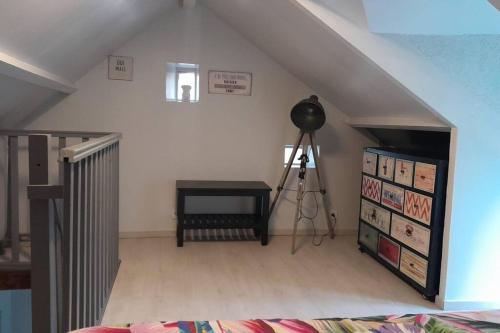 Cette chambre mansardée dispose d'un escalier, d'une table et d'un tripode. dans l'établissement Charmante maisonnette au cœur de la campagne, à Pourrain