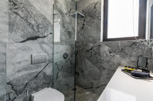 a bathroom with a shower with a toilet and a sink at GM exclusive Luxury Suites & SPA in Sitia