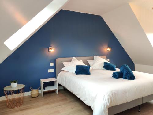 una camera da letto con parete blu e un letto con cuscini blu di Maison wifi jardin arboré pointe du Raz a Plogoff
