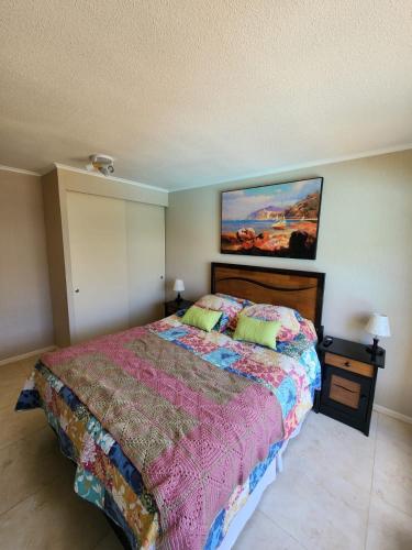 a bedroom with a bed and a painting on the wall at Departamento Laguna Vista Oceano in Algarrobo