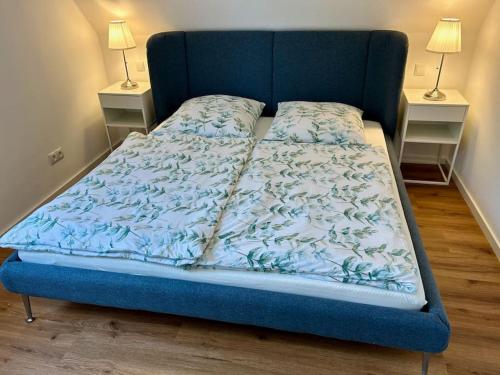 a bed with a blue bedspread and two night stands at Licht+Luft, Wohnen auf Zeit in Bad Nauheim