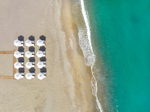 uma vista sobre uma praia com cadeiras na areia em Calla Luxury Seafront Suites em Retimno