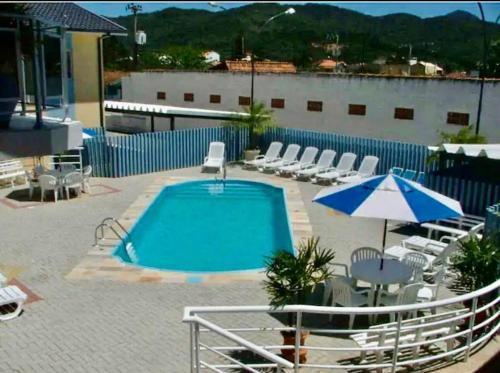 a swimming pool with chairs and an umbrella at AP com Piscina em Porto Belo in Porto Belo