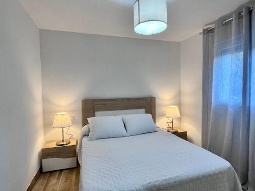 sypialnia z białym łóżkiem i 2 lampami w obiekcie Dolmen w mieście Serradilla del Arroyo
