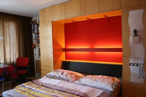Schlafzimmer mit einem Bett mit einem orangefarbenen Kopfteil in der Unterkunft MicroAppartment with bath and cozy balcony in Davos