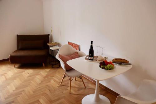 einen weißen Tisch mit einer Schale Obst und einer Flasche Wein in der Unterkunft Cozy Flat in Piemonte in Acqui Terme