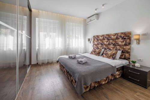 ein Schlafzimmer mit einem großen Bett mit einem großen Kopfteil in der Unterkunft Silver Apartment in Novi Sad