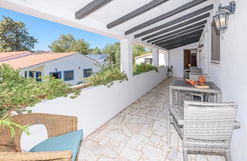 a patio with a table and chairs on a white wall at Quinta de São Pedro in Sobreda