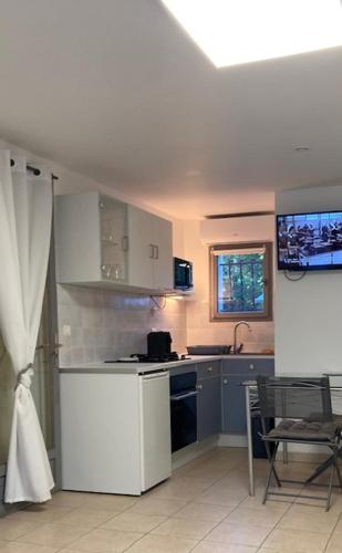 une cuisine avec des armoires blanches et une table et des chaises dans l'établissement STUDIO PIED DANS L EAU, à La Londe-les-Maures